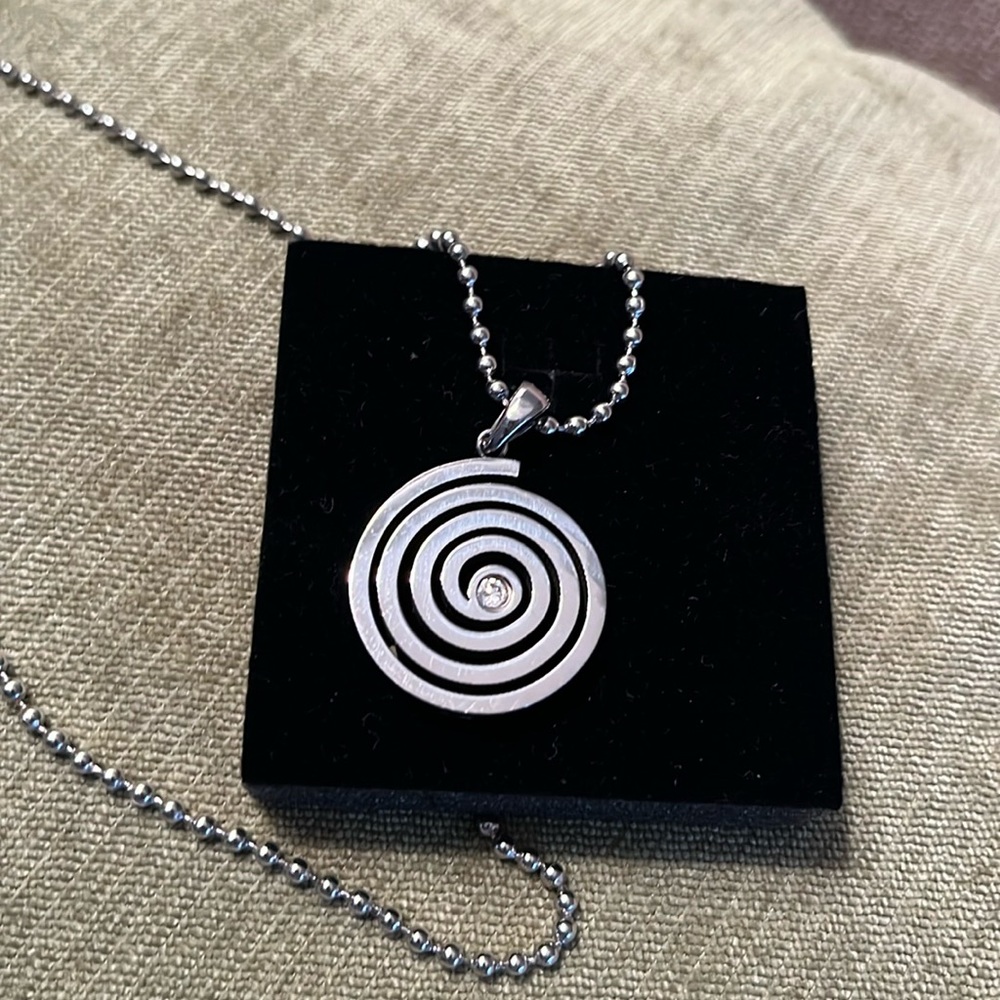 Silver necklace in round swirl pattern with diamond like stone in the middle